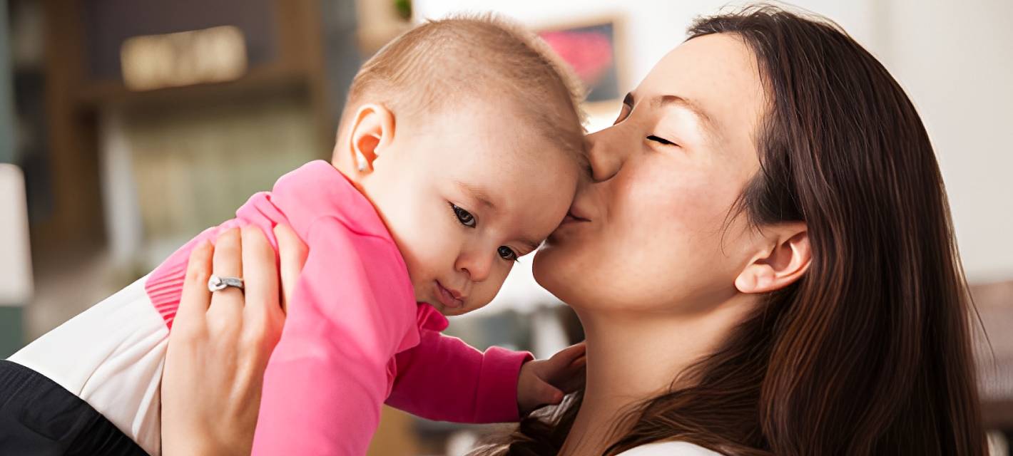 Woman holding and kissing infant