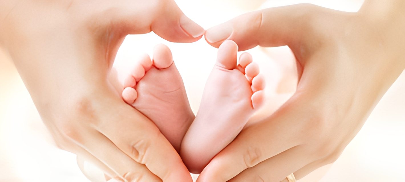 Heart-shaped hands around tiny baby feet